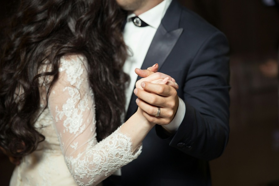 Bride and groom holding hands closely during their first dance