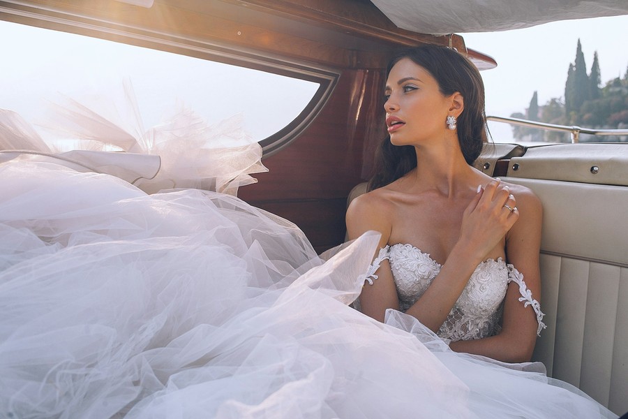 Bride in a lace gown seated in a vintage car