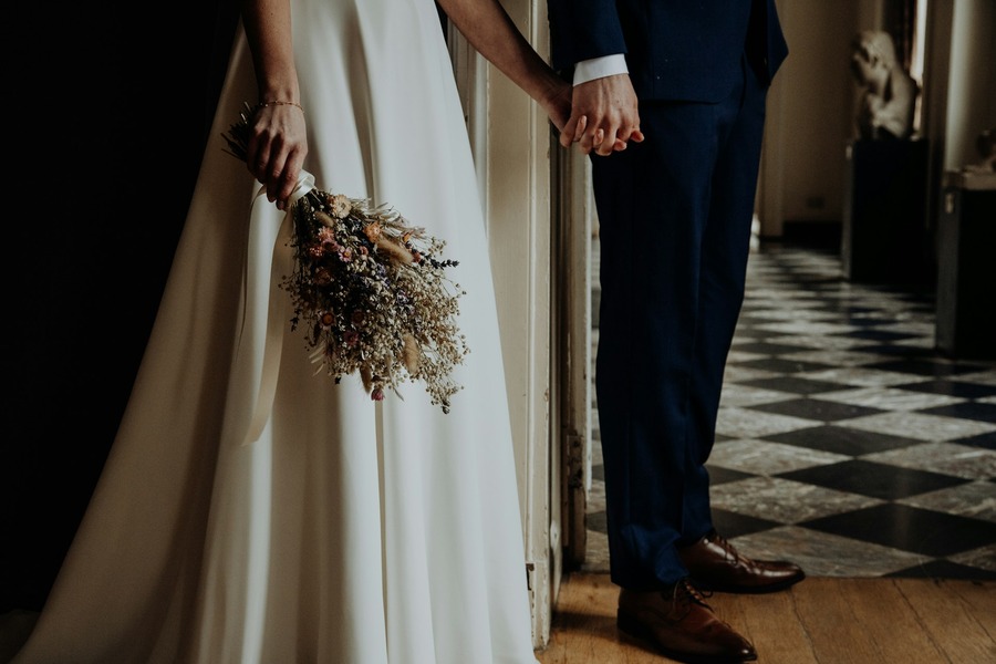 Bride and groom holding hands with a dried flower bouquet