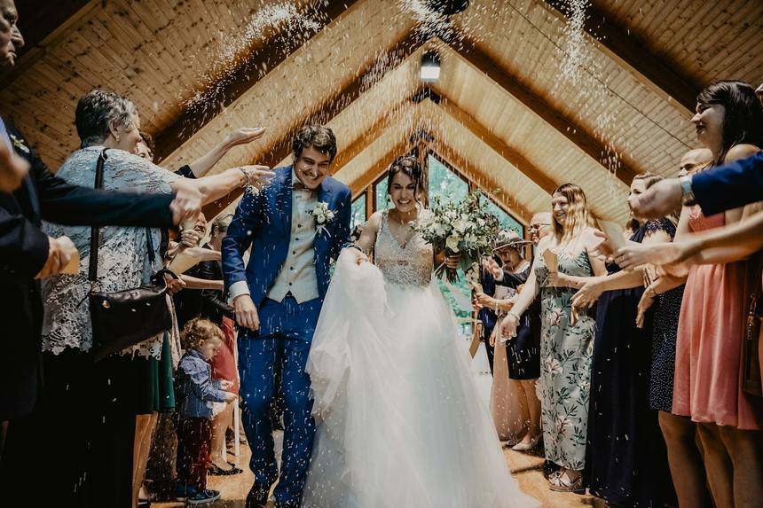 Guests throwing confetti over the newlyweds leaving the ceremony