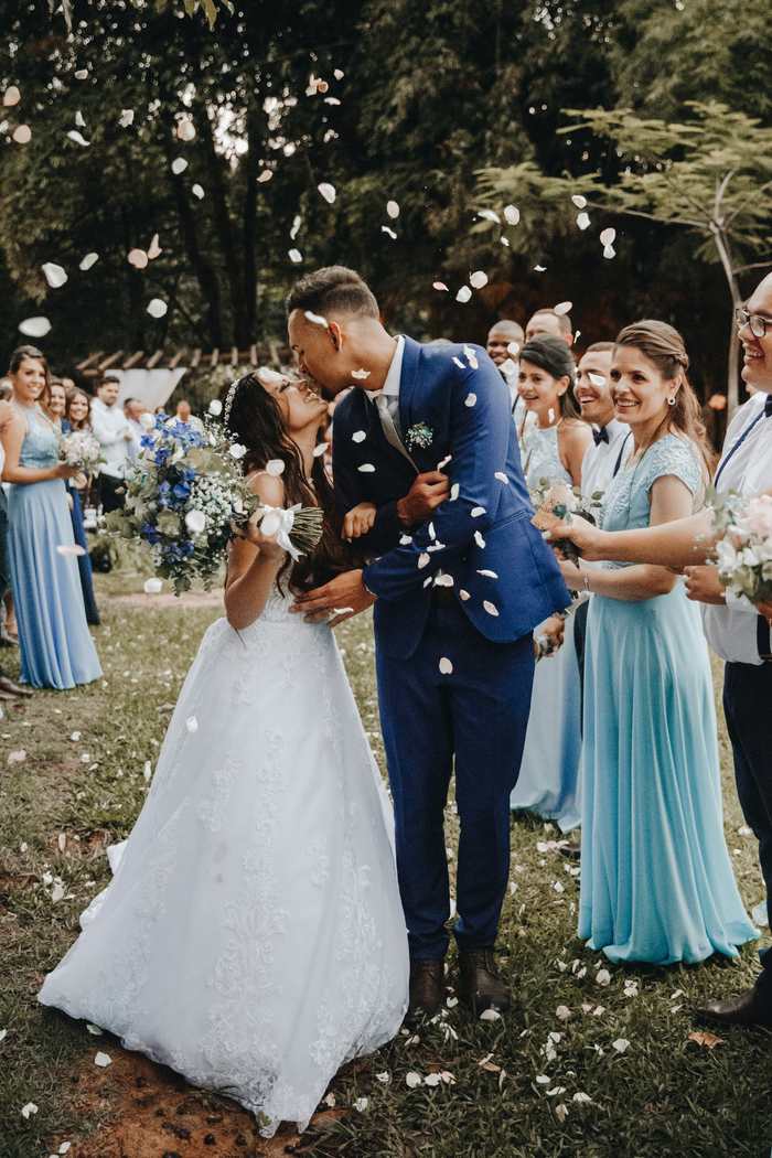 Newlyweds kissing as their guests throw petals