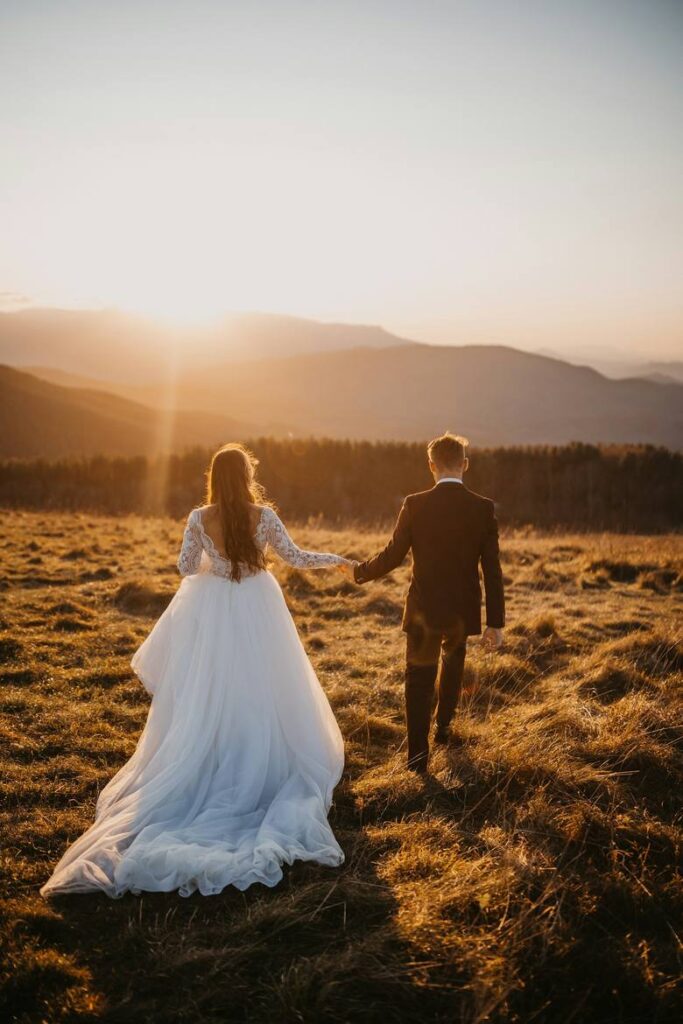 Couple walking hand in hand through a field at sunset