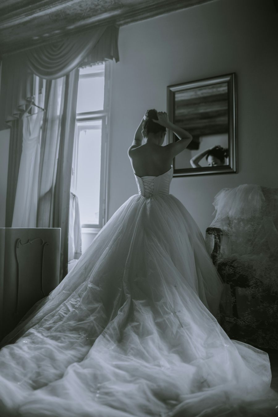 Bride facing a window with her long train spread across the floor