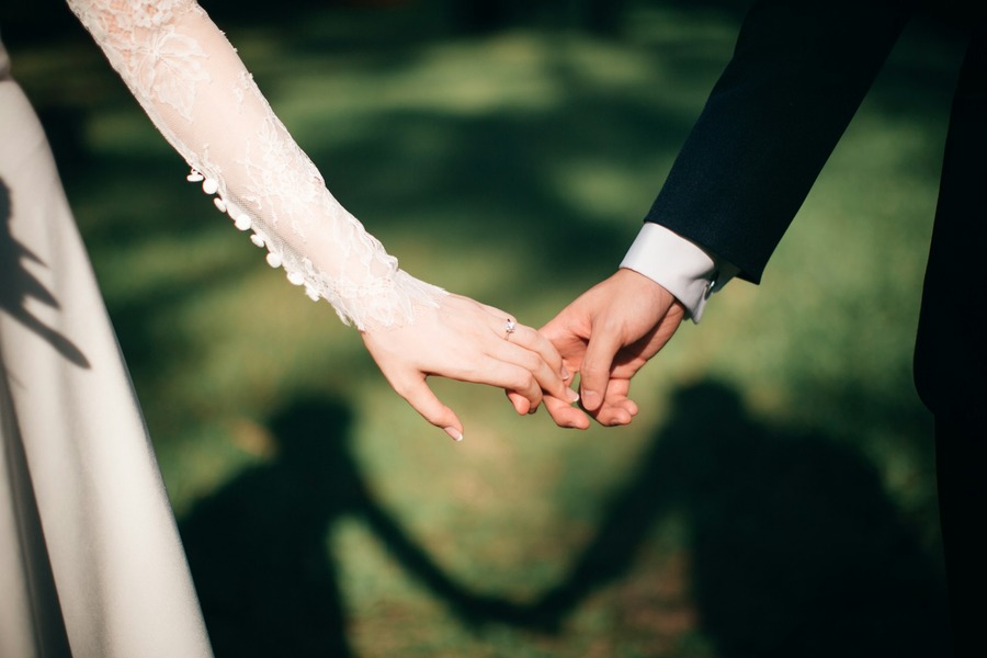 Couple holding hands with their shadow falling on the grass
