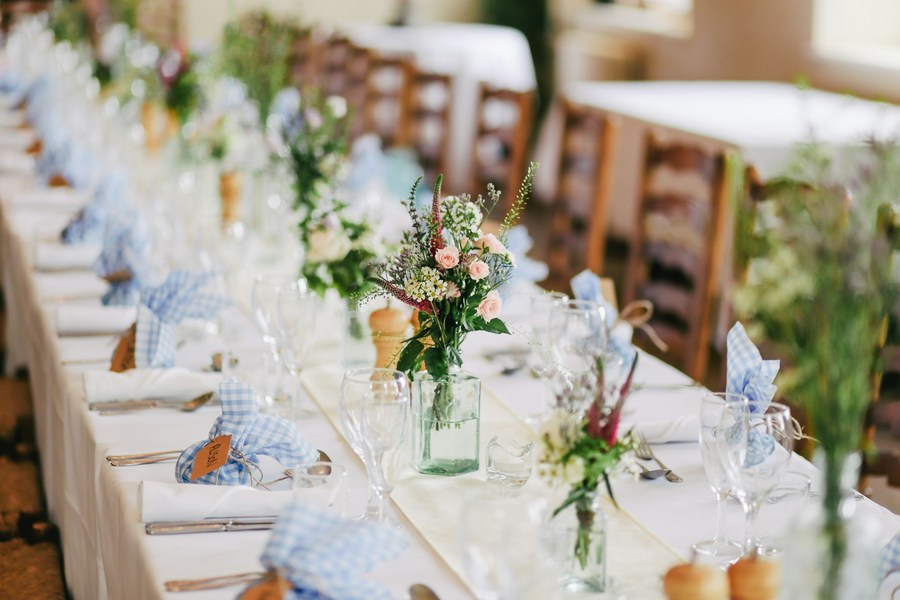 Reception table dressed with blue ribbon and wildflowers